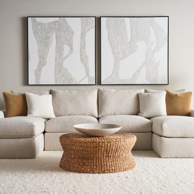 Neutral-toned Rowe sectional sofa with chaise, paired with a woven round coffee table, modern abstract wall art, and soft accent pillows in a cozy living room.